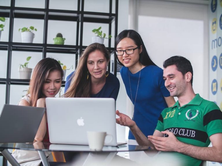 Menschen lächeln, während sie auf den Laptop schauen Feature Image For: Cara Merekrut Karyawan yang Efektif dan Efisien