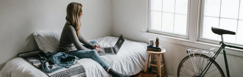 student working on her bed