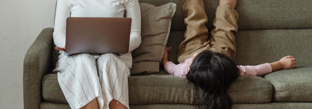 mom works from home while kid plays on the couch