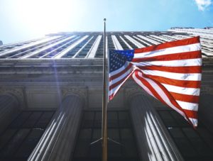 Bottom-up shot of the US flag against a neo-classical building. Feature Image for "20 Best Job Sites in the US"