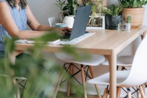Woman working on her dining room table at home. Feature Image for "7 Best Strategies for the Remote Modern Workforce"