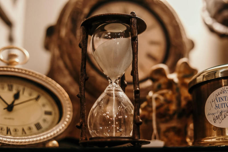 Image of an Hourglass amidst other clocks and timepieces.