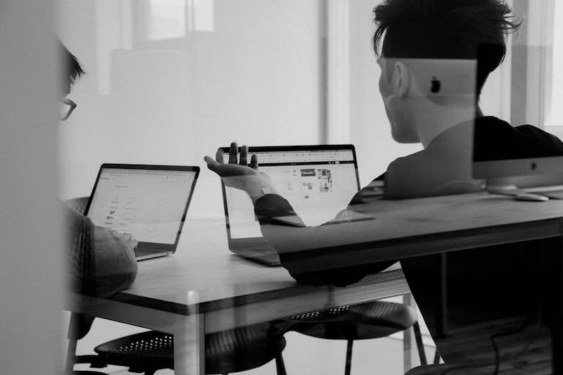 two men talking and starring in their laptops Feature Image For: When To/Not to Explore Further Studies as Working Adults