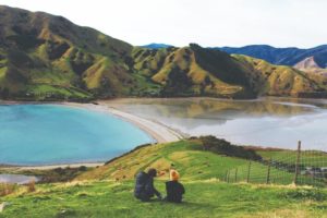 two people sitting on the grass looking at the view of New Zealand Feature Image For: The Complete Guide to Part-Time Work from Home Jobs in New Zealand