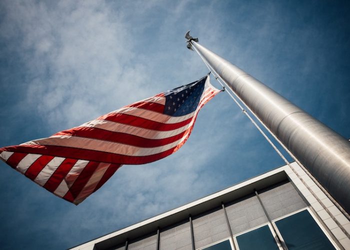United States Flag flying against blue sky background. Feature image for "Complete Guide to Government Jobs in the United States"