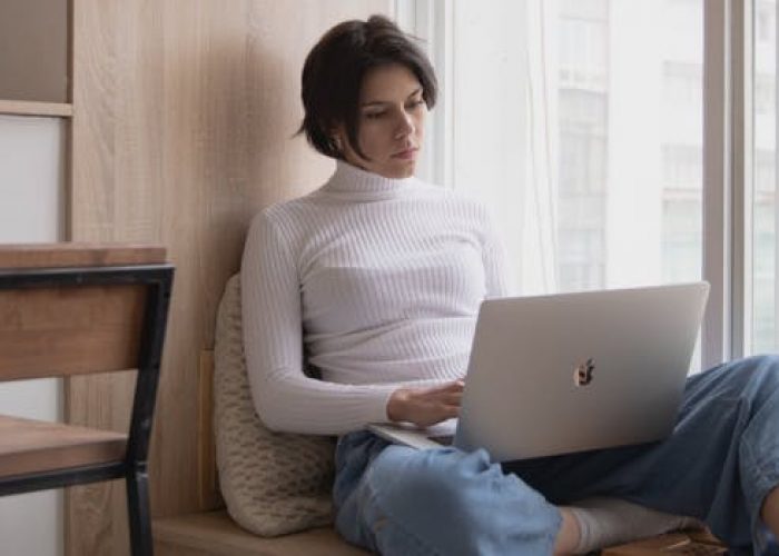 woman looking for work-from-home jobs on her laptop by the window